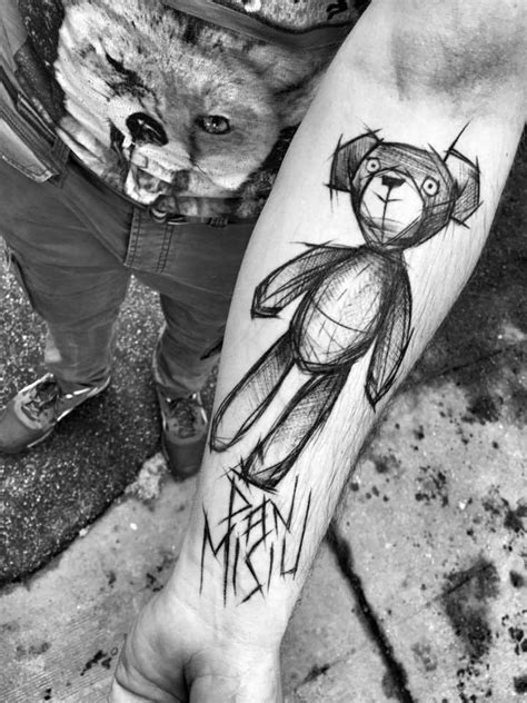 A Person With A Tattoo On Their Leg Holding A Teddy Bear And Wearing A Hat