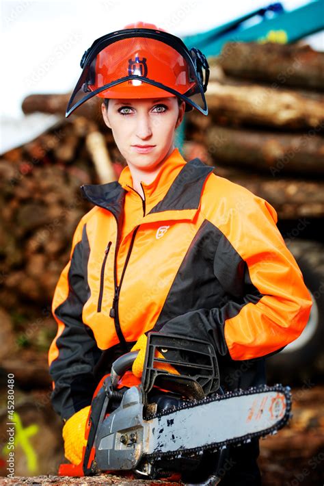 Junge attraktive Frau mit Motorsäge in Schutzkleidung Stock Photo