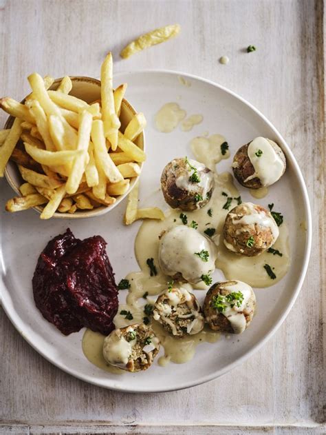 A White Plate Topped With Meatballs And Fries Next To A Bowl Of Ketchup