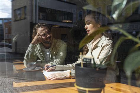 Geschäftsfrau im Gespräch mit einem Kollegen am Tisch in einem Café