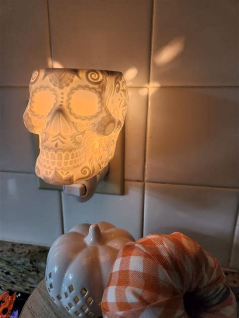 A Light That Is On The Wall Next To A Potted Plant And A Pumpkin