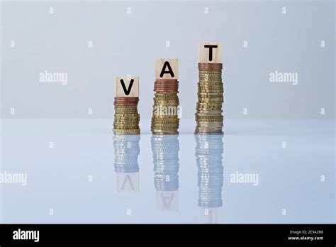 Word Vat On Wooden Blocks On Top Of Ascending Stacks Of Coins On Gray