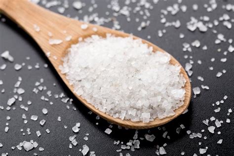 Crystals Of Shallow Salt In A Scoop Spoon On A Dark Gray Table