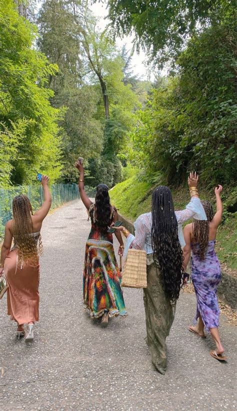 Three Women Walking Down A Road With Their Arms In The Air And One