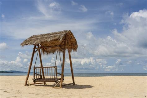 Wooden Swing Under A Thatched Roof On A Sandy Tropical Beach Near Sea