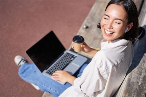 Hermosa joven estudiante asiática sentada con una computadora portátil