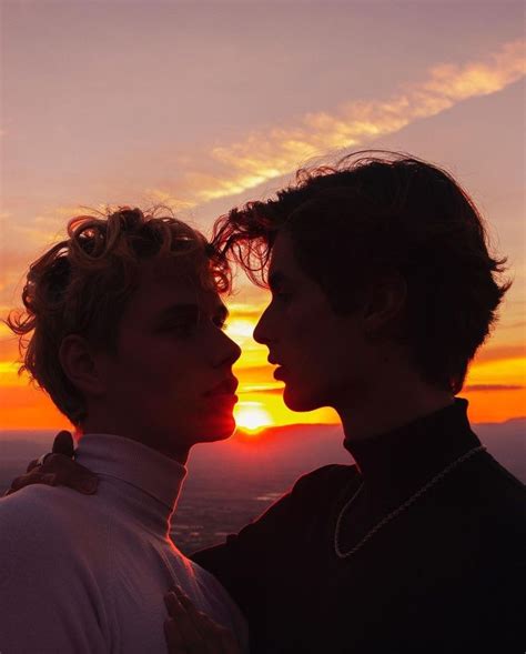 Two People Standing Next To Each Other With The Sun Setting In The