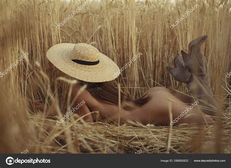 Mujer desnuda acostada en un campo con sombrero fotografía de stock