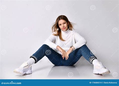 Teenage Female In Jeans Sweater Socks And Sneakers Smiling Sitting