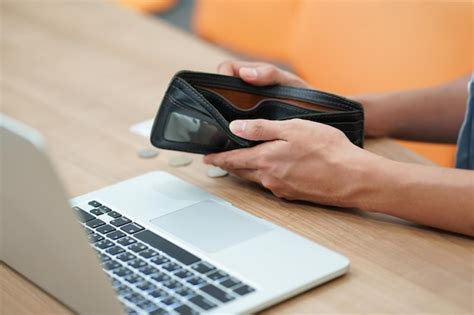 Mãos Cortadas Segurando Carteira Vazia Na Mesa Por Laptop Foto Premium