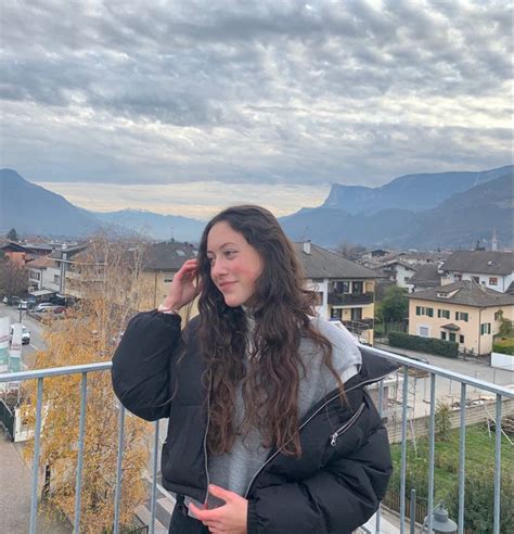 A Woman Standing On Top Of A Balcony Talking On A Cell Phone With