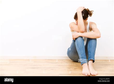 Depressed Sad Young Woman Sitting On Floor Holding Her Head Stock