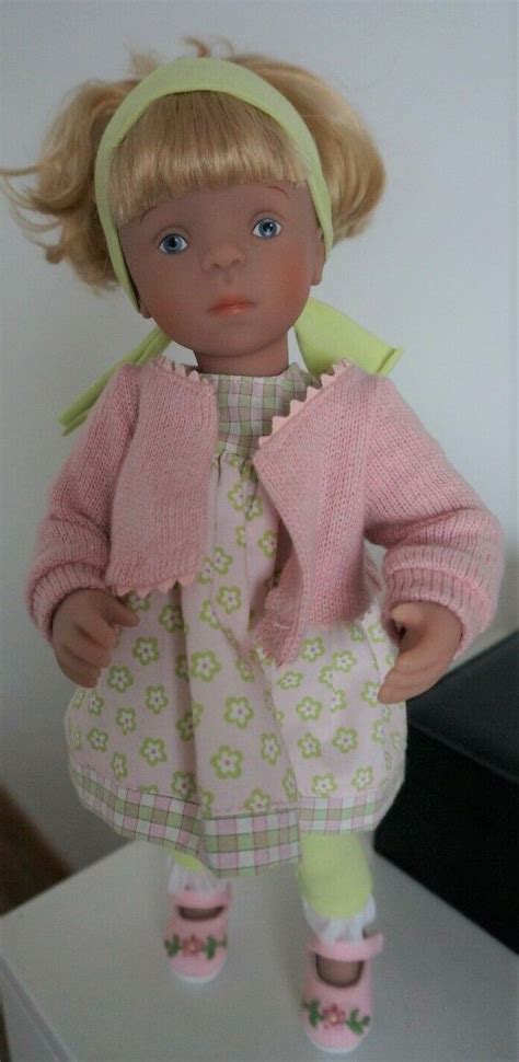 A Doll With Blonde Hair Wearing A Pink Dress And Green Headband On Top