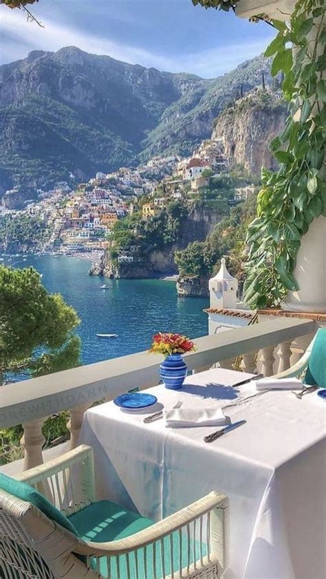 An Outdoor Dining Area With Table And Chairs Overlooking The Water