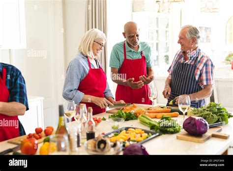 Happy Group Of Diverse Senior Friends In Aprons Talking During Cookery