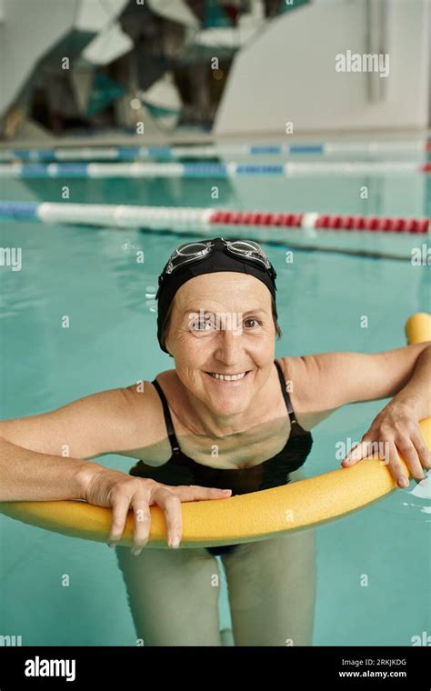 Happy Middle Aged Woman Swimming With Pool Noodle Swim Cap And Goggles