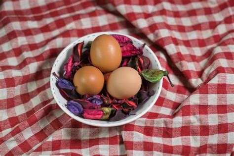 Tres huevos en un bol sobre un paño a cuadros rojo y blanco Foto Premium