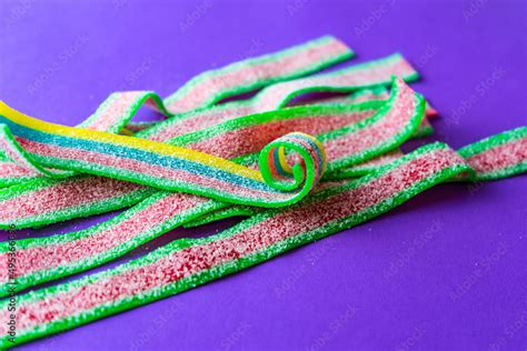 Rainbow Stripes Of Sour Jelly Candies In Sugar Sprinkles On A Purple