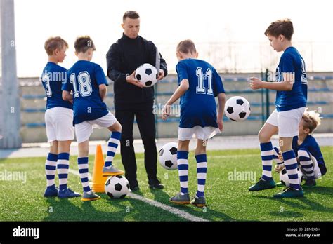 Young coach teaching kids on football field. Trainer explains to ...