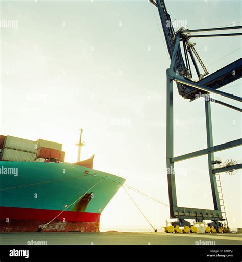 A Large Freight Ship Loaded With Containers At The Quay Side A Crane