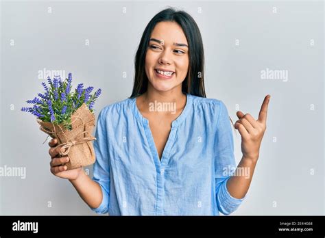 Young Hispanic Girl Holding Lavender Plant Smiling Happy Pointing With