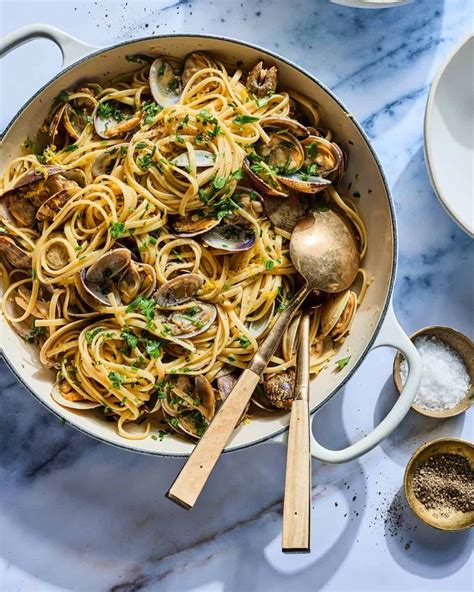 Linguini with Clams in a large braiser with serving spoons and plates ...