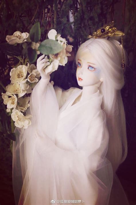 A Doll Dressed In White And Holding Flowers