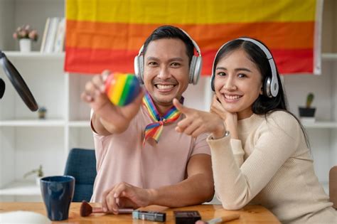 Um gay asiático atraente e feliz segurando o coração lgbt em seu quarto sua amiga Foto Premium