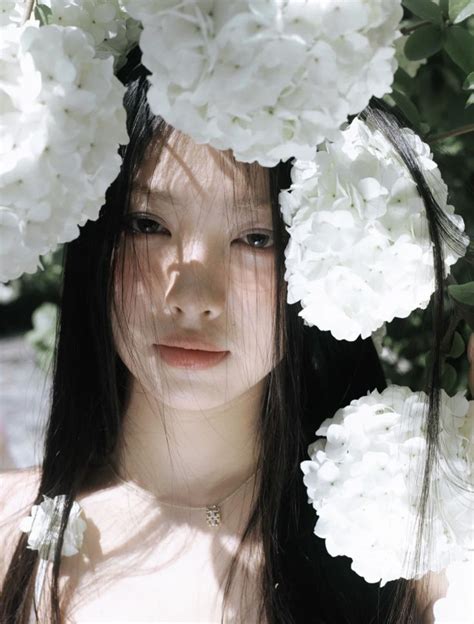 A Woman With Long Black Hair And White Flowers In Her Hair Is Looking