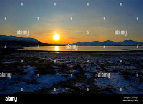 Deep Vibrant Golden Sunrise Over Fjord And Snowy Mountain Landscape