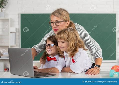 School Teacher With A Schoolkids Learning At Laptop Computer Teacher