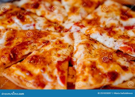 Toasted Cheese Pizza Cut Into Pieces On A Wooden Round Cutting Board