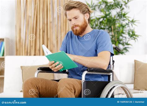 Joven En Silla De Ruedas Leyendo Libro En Interiores Foto De Archivo