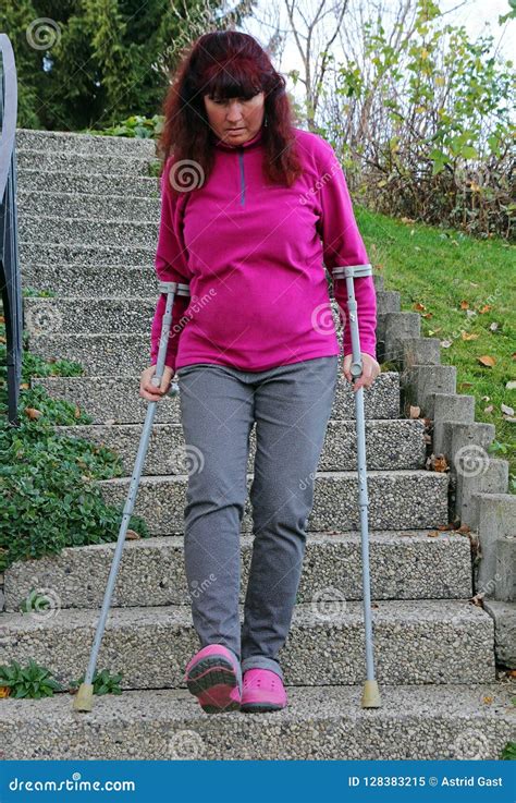 A Woman Walking Down a Staircase with Crutches Stock Image - Image of ...