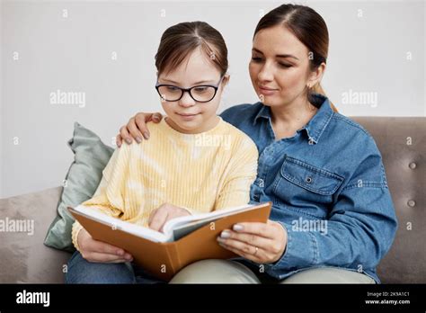 Portrait Of Teen Girl With Down Syndrome Reading Book With Loving