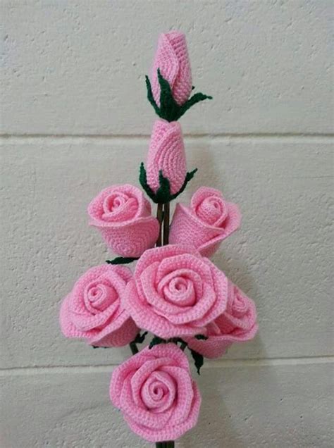 Pink Crocheted Roses Are Arranged In A Vase Against A White Brick Wall