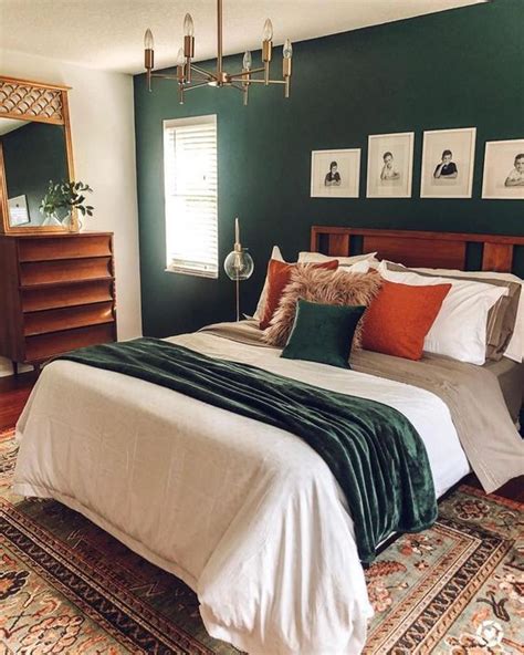 a mid century modern bedroom with a dark green accent wall, a stained ...