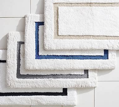 four white and blue bathroom rugs are on the floor in front of a tiled wall