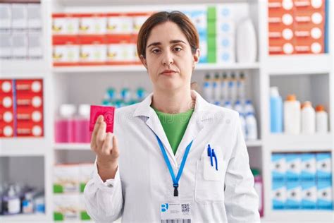 Brunette Woman Working At Pharmacy Drugstore Holding Condom Thinking