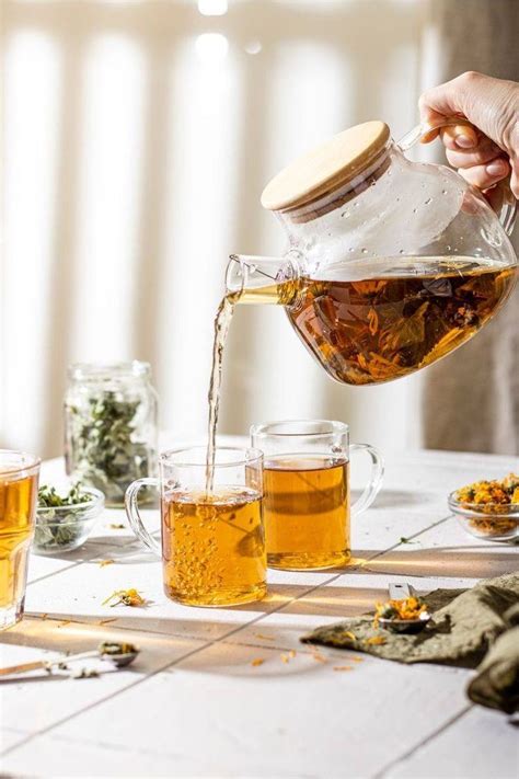 A Person Pouring Tea Into Cups On A Table