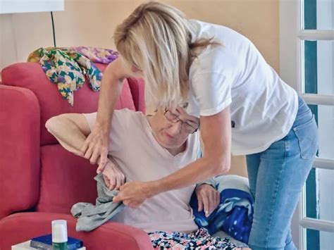 Una anciana de 83 años en su sillón y la enfermera geriátrica la ayuda 2024