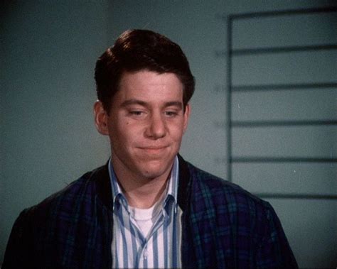 A Man In A Blue And White Shirt Is Looking At The Camera With A Smile