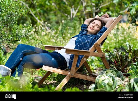 Young Woman Sleeping On Chair In Organic Vegetable Garden Stock Photo