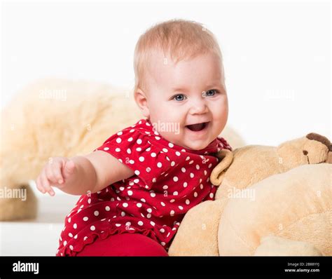 Front view of cute child sitting next to toy bear and laughing ...