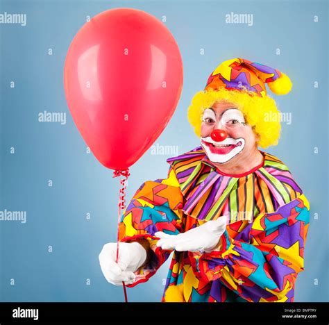 Friendly clown hands you a bright red balloon Stock Photo - Alamy