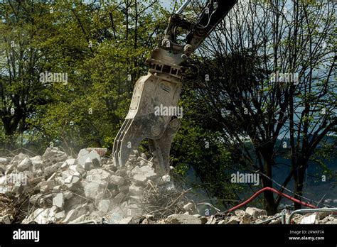 Excavator Demolishing Building With Large Claws On Sunny Day Stock