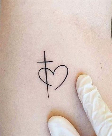 A Cross And Heart Tattoo On The Side Of A Woman S Right Arm