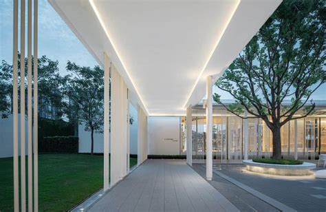 An Empty Walkway In Front Of A Building With Columns And Lights On The