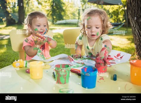 Two Year Old Girls Painting With Poster Paintings Together Against