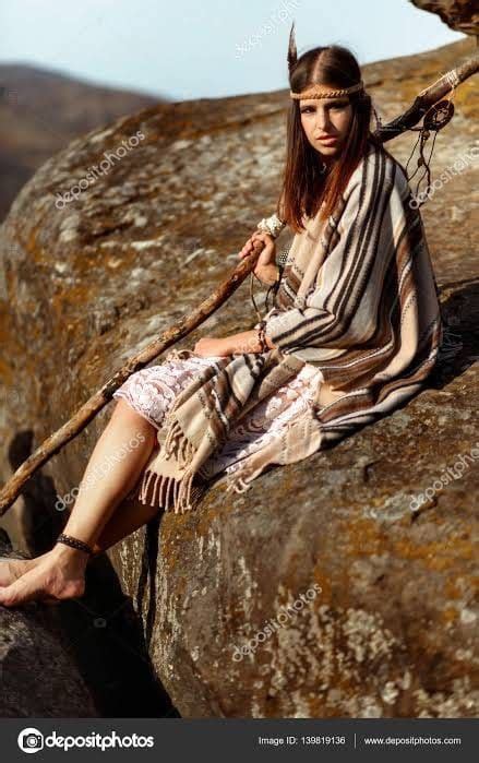 A Woman Sitting On Top Of A Large Rock Next To A Tree Branch And